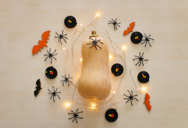 万圣节假期的照片。木制的白色桌子上挂着南瓜和金色的花环灯。俯视图，平放图片下载