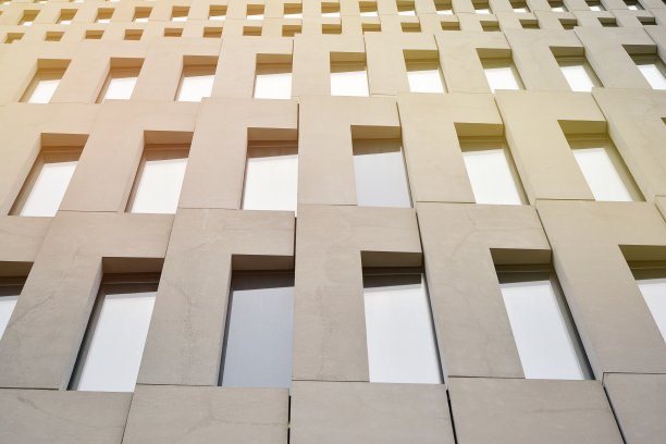 透视几何角度的混凝土窗户在立面上的一个现代主义野兽派风格的建筑表面与阳光。图片下载