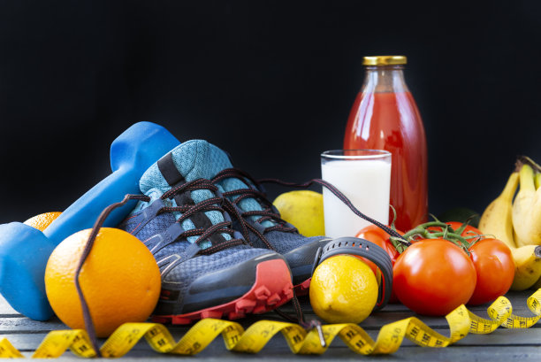 蓝色运动鞋，哑铃，水果，蔬菜，卷尺，食物，柠檬，橙子，西红柿，香蕉，一瓶番茄汁，一杯深色背景的牛奶，运动手链图片下载