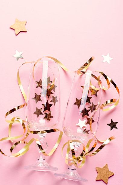 圣诞贺卡与香槟玻璃与五彩纸屑和流光在粉红色和金色图片下载