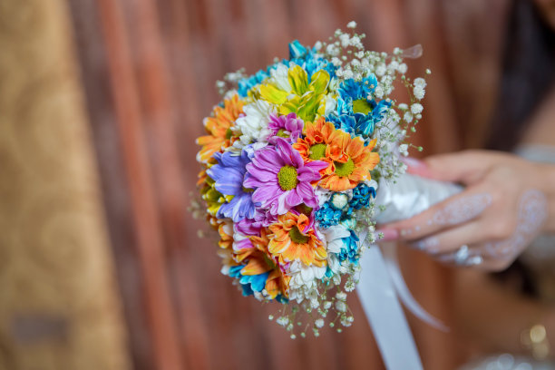 他手里拿着一朵结婚花。彩色微距照片详细的花束与色彩丰富的玫瑰，白色的小花和假钻石在玫瑰的中心。图片下载