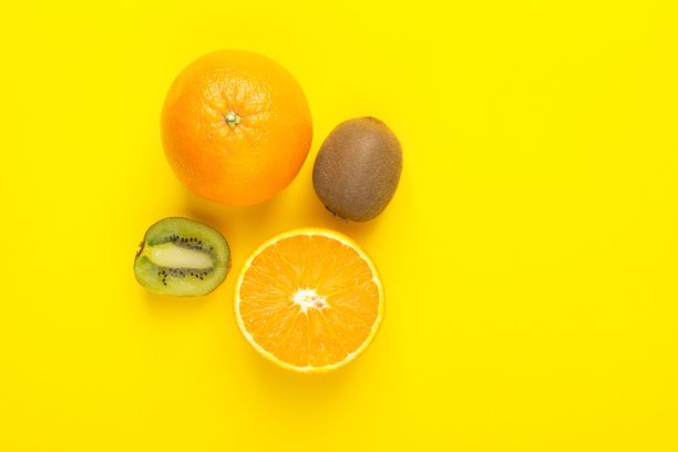 成熟多汁的整体和对半的橙子猕猴桃，明亮的黄色背景。维生素健康饮食排毒素食热带水果的概念。海报横幅模板与复制空间图片下载