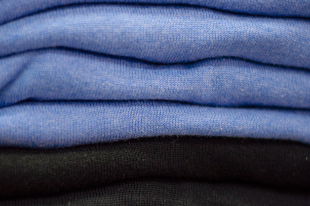 暖和的衣服整齐地叠在货架上。汗衫、毛衣、套头衫、开襟羊毛衫、帽衫、胸围帽都堆在架子上。衣服存储。尺寸范围。图片下载