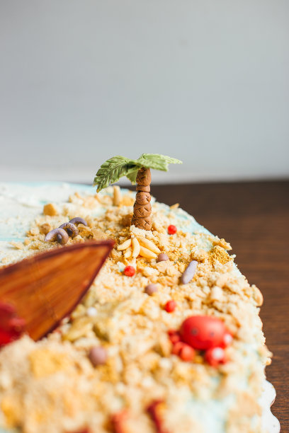 一个多层蛋糕放在一个绿松石的甜点平台和一张木桌上。航海主题,冲浪图片下载