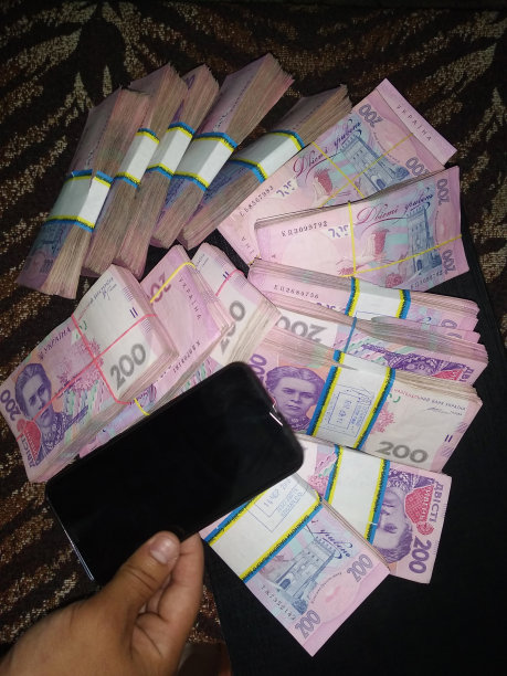 很多乌克兰钱和一部手机，面值200格里夫纳的一包包钱，互联网盈利概念图片下载
