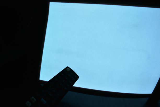 具有电致发光涂层的夜光A4纸以不同的平面排列在原始光滑的表面上，有一只母手和一个遥控器。出色的彩色底色，彩色基材，发光均匀。图片下载