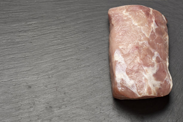 在黑色石板背景上的生猪肉。肉质清晰可见。图片下载