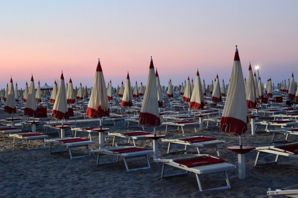 红色和白色的太阳伞，五颜六色的海滩。许多太阳伞和太阳床图片下载