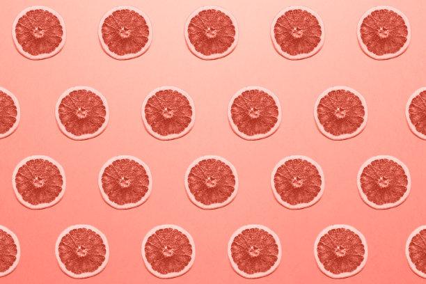 时髦的夏季图案与多汁的葡萄柚在明亮的光珊瑚背景。以彩色纸为背景的简约风格。彩色照片。最小的创意概念。柔和的颜色。活的珊瑚图片下载