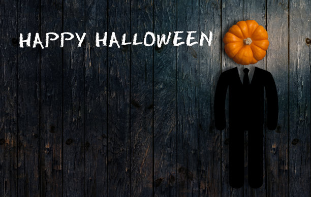 木制背景上的南瓜作为人的头，并写着“万圣节快乐”图片下载
