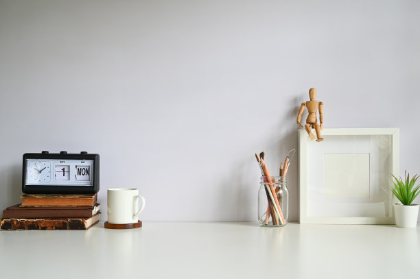 工作空间的相框，咖啡，闹钟，书籍和植物装饰在白色的桌子上。图片下载