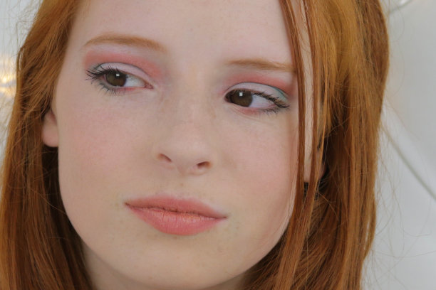 这张照片是一个14 / 15岁的红发少女，皮肤苍白，脸上有雀斑。她坐在卧室里测试眼睑上眼影的颜色，用裸唇画了夸张的眼妆，社交媒体上的化妆视频展示了全脸化妆产品的结果图片下载