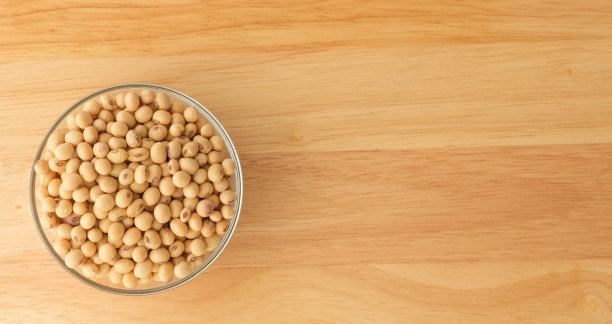 大豆装在一个杯子里，放在一张有复印空间的木桌上图片下载