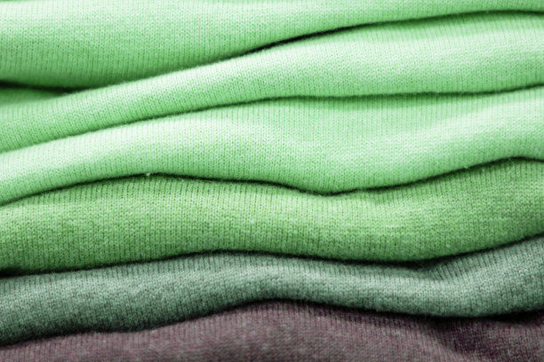 暖和的衣服整齐地叠在货架上。汗衫、毛衣、套头衫、开襟羊毛衫、帽衫、胸围帽都堆在架子上。衣服存储。尺寸范围。图片下载