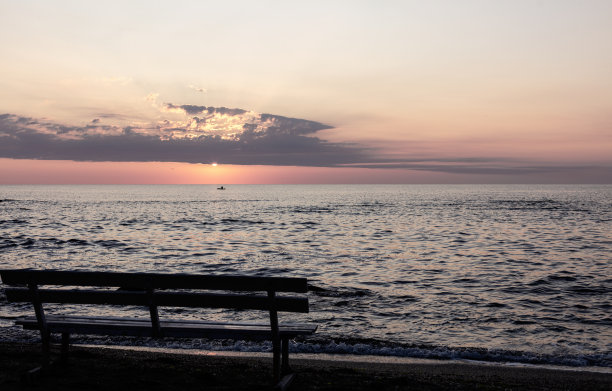 美丽的日落(日出)在海上，美丽的海浪和海滩长椅的轮廓。图片下载