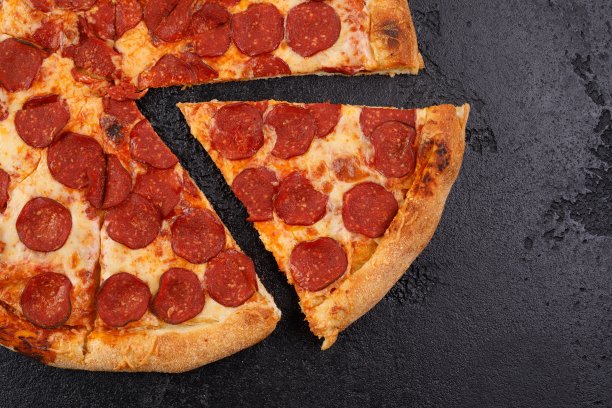 传统的意大利香肠披萨上的黑色纹理背景。特写镜头。美味食物的概念。图片下载