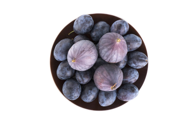 青梅和无花果的果实。孤立的成熟果实放在棕色的盘子上，白色的背景图片下载