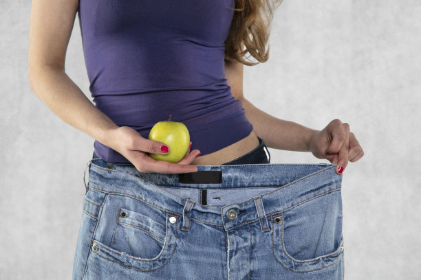 年轻的运动女性轮廓，苹果和老大裤子图片下载