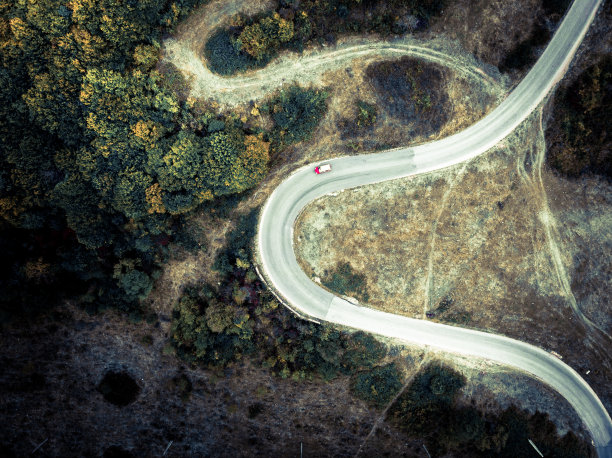 鸟瞰图的汽车驾驶在蜿蜒的道路通过农村荒野图片下载