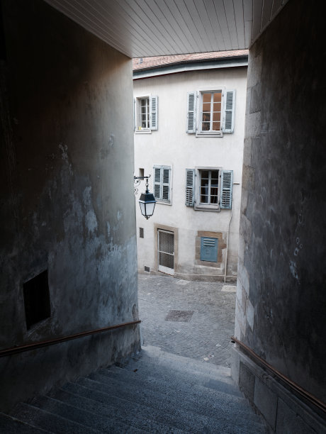 从瑞士日内瓦老城一条狭窄的有楼梯的小巷中看到的中世纪铺成的街道和一幢带有木制百叶窗的窗户的老房子。图片下载
