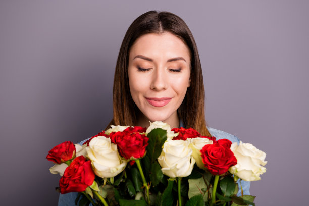 我男朋友送的漂亮玫瑰。近距离的照片和平冷静积极的女士拿着一束花玫瑰气味享受气味穿牛仔牛仔裤衣服衬衫孤立的灰色背景图片下载