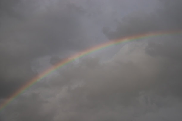 灰色天空上的天然彩虹。下雨的一天。图片下载