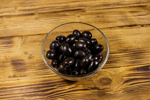 腌黑橄榄放在木桌上的玻璃碗里图片下载
