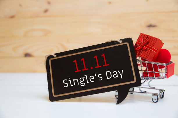 中国网上购物，双十一光棍节销售理念。购物车和红心枕头在白色和棕色的背景与文本拷贝空间11.11光棍节销售。图片下载