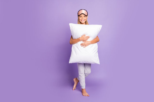 积极开朗的孩子的全尺寸照片拥抱拥抱柔软的枕头享受过夜的聚会感觉梦想，梦想的和平的平静穿着风格的t恤裤子睡觉的面具隔离在紫色的背景图片下载