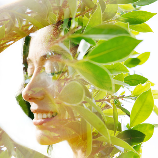 闭上眼睛，用手触摸头发，双重曝光一个放松的自然美的轮廓，加上明亮的绿色热带树叶图片下载