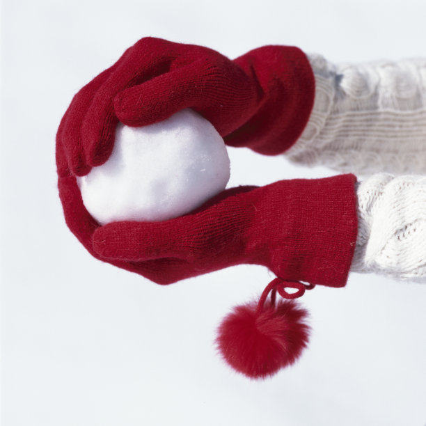 女人的手戴着红色针织手套拿着雪球。人们在冬天在户外玩雪。女装冷天时尚配饰。图片下载