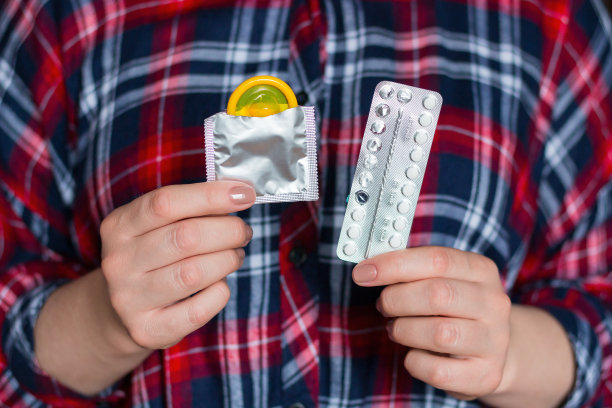 年轻女子拿着避孕药-避孕套和避孕药图片下载