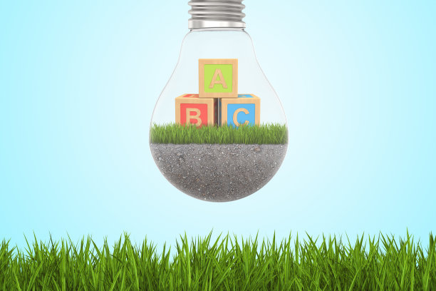 灯泡的3d渲染与儿童字母块内在绿色草地和蓝天的背景图片下载