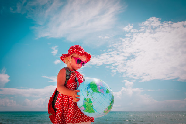 孩子们在海滩上旅行，小女孩在海上带着地球仪图片下载