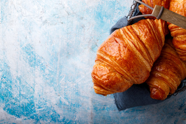 欧式早餐，金属篮子里的新鲜牛角面包，美味的街边小吃。顶部视图复制空间的文本图片下载