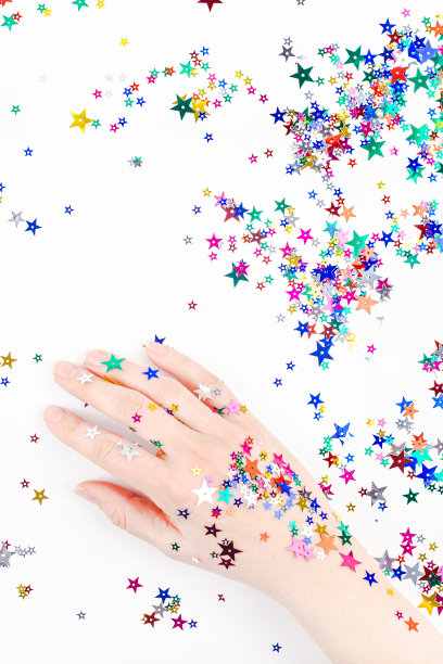 女人手里拿着节日色彩的星星纸屑图片下载