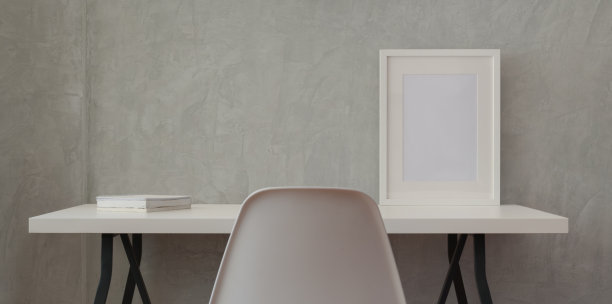 阁楼工作场所与白色木制书桌和模拟框架和白色的书在灰色的墙壁图片下载