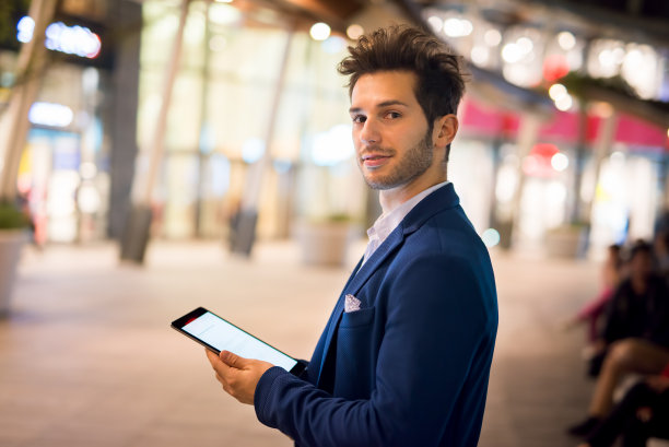 一个晚上在城市里用平板电脑的男人的肖像图片下载