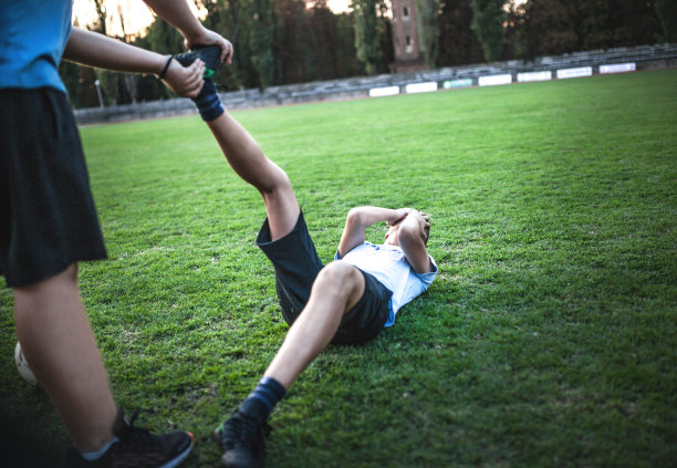受伤的足球运动员因脚踝受伤躺在场上图片下载