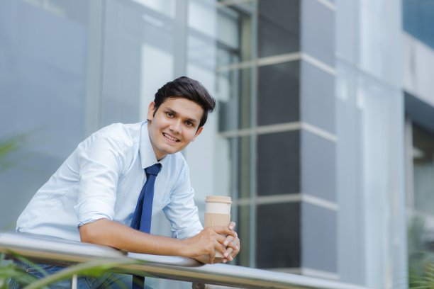 在阳台端着咖啡杯的商人照片图片下载