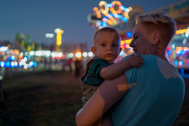 快乐的妈妈和宝宝在游乐园晚上的肖像图片下载