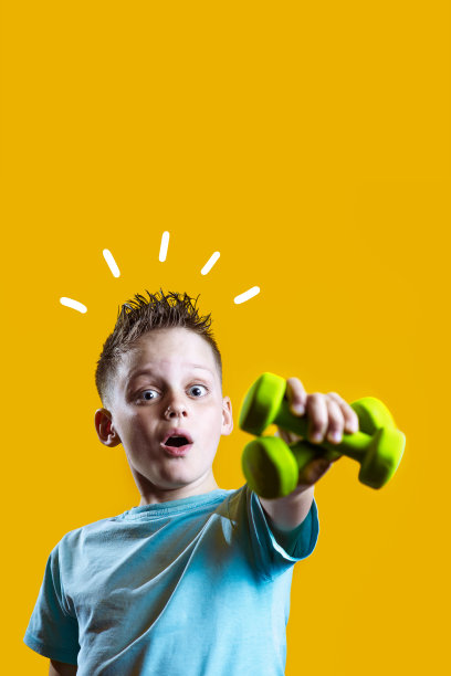 一个穿着亮t恤黄色背景上有哑铃的男孩图片下载