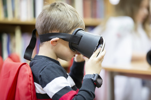 一个孩子看着虚拟眼镜。男孩戴着虚拟现实VR眼镜看电影或玩电子游戏图片下载