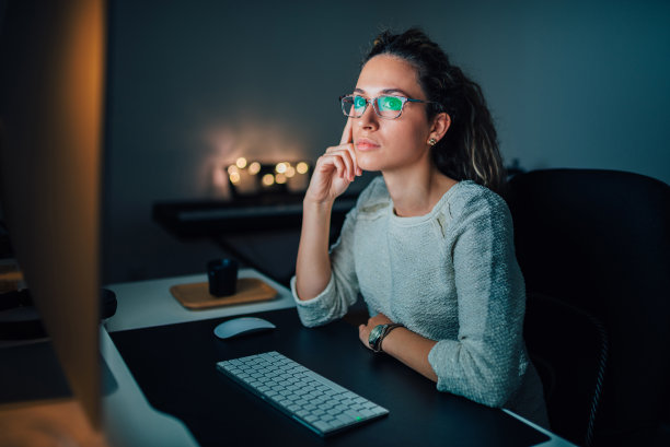 严肃的女经理晚上看着办公室的电脑屏幕。图片下载