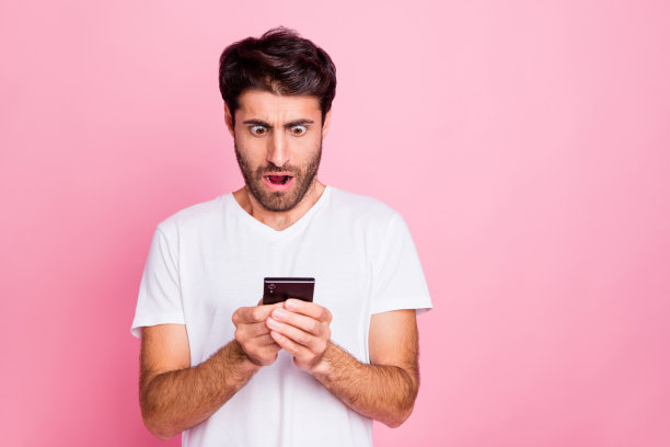 一名中东男子用他的智能手机看了一下照片，看到了反馈，听到了新闻评论，尖叫着，哇哦，我的天哪，穿一件风格独特的夏装，在粉红色的背景上图片下载