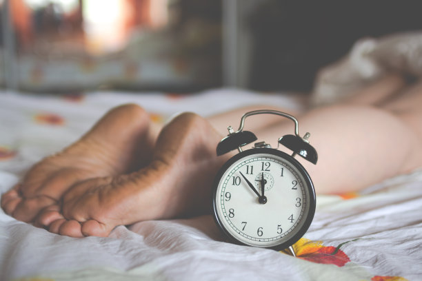 一个时钟和一个熟睡女人的脚。图片下载