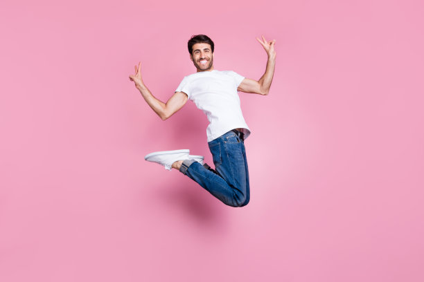 全尺寸照片积极开朗，时髦的中东男子跳有自由时间，感觉内容情绪，使v-符号穿时尚的时尚风格的服装孤立在粉红色的背景图片下载