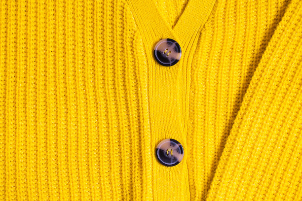 黄色橙色芥末赭色针织羊毛纹理背景。冬季或秋季毛衣或套衫与钮扣近距离图片下载