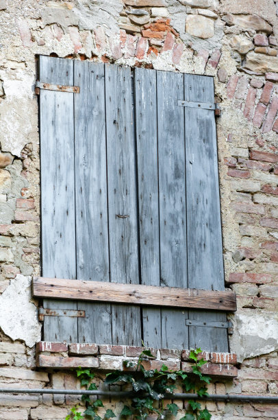 乡村住宅的窗户细节，在砖墙和古老的石头上有开裂的油漆和生锈的铰链。图片下载