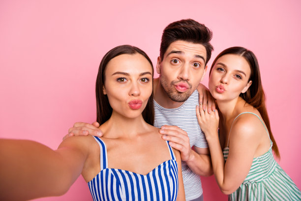 近距离的照片可爱的青年使照片视频通话发送飞吻穿着条纹t恤连衣裙小品孤立在粉红色的背景图片下载